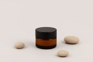 a jar of cream next to some round white stones